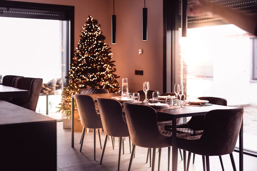 Elegante sala da pranzo in periodo natalizio. Albero di Natale illuminato, grandi finestre sul cortile con piscina.